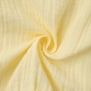 Macro shot of yellow tiered muslin skirt fabric showing soft texture and pleated details