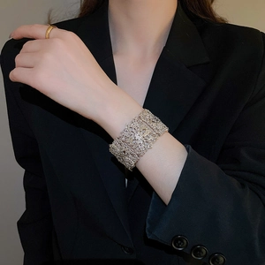 Gros plan détaillé sur la gravure de fleurs ajourées d'un bracelet manchette argenté