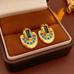 Détail de boucles d'oreilles vintage en or avec pierres bleu marine dans un écrin