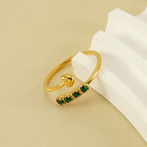 Gold plated open ring with heart motif and green zircon stones on white steps
