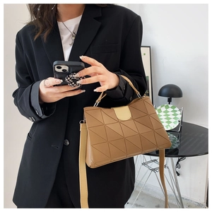 Close-up of brown quilted leather bag with beige flap on model wearing black blazer
