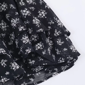 Close-up of black floral chiffon dress showing tiered ruffle layers and fabric texture