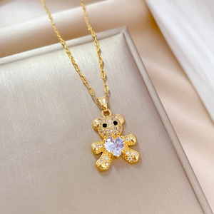 Detail of gold-tone bear pendant necklace with sparkling pavé zircons and heart stone