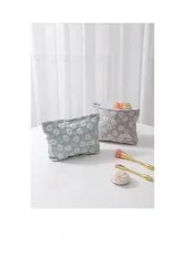 Détail de trousses de maquillage en toile avec broderie marguerite en vert et mauve