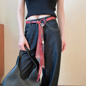 Close-up of red leather waist belt with printed silk scarf tassel and metal ring buckle