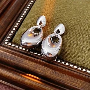 Macro detail of glossy water drop earrings on a vintage green velvet background