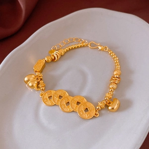 Detailed view of sand gold bracelet with copper coins and lucky charms on silk background