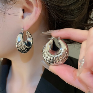 Macro shot of silver geometric textured hoop earrings with a mirror-polished quilted finish