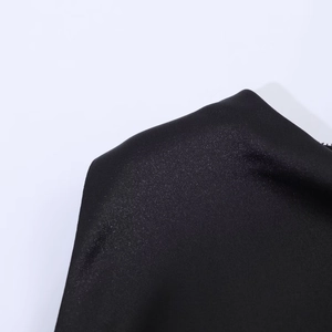 Close-up of the black satin fabric texture and shimmering tassel details on the evening dress