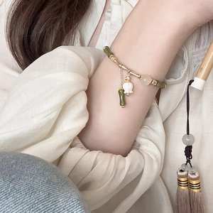 Detailed view of bamboo joint bracelet with lily of the valley floral charm on wrist