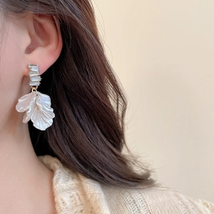 Dettaglio di orecchini a fiore placcati in oro con perle e cristalli indossati da una modella