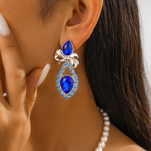 Macro detail of luxury blue crystal teardrop earrings with a sparkling diamond bow design