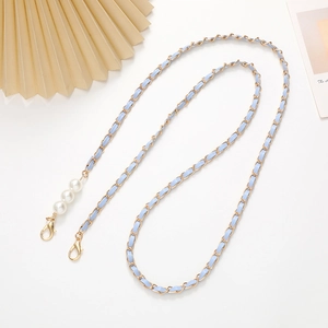 Detail of light blue leather woven metal chain with white faux pearls and gold clasps