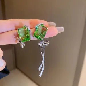 Asymmetric silver earrings with emerald green gemstones and crystal bow tassels