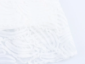 Detail shot of white mesh fabric featuring elegant 3D wavy texture and lace embroidery