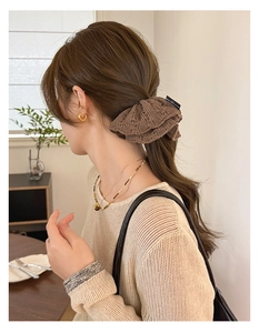 Detailed view of coffee brown knitted hair scrunchie with lace texture on a bun
