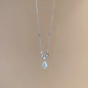 Detail view of water drop pendant with light blue stone and shimmering crystal accents