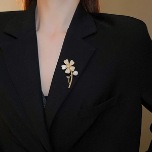 Détail d'une broche papillon en nacre dorée portée sur le revers d'un blazer noir élégant