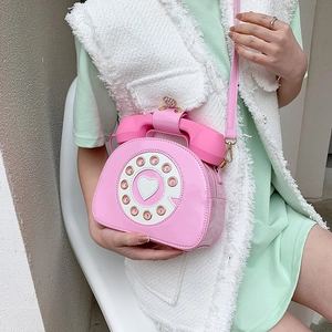 Detail of creative pink patent leather crossbody bag in vintage telephone shape