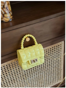 Close-up of a yellow mini quilted jelly bag with metal chain on a wooden handle