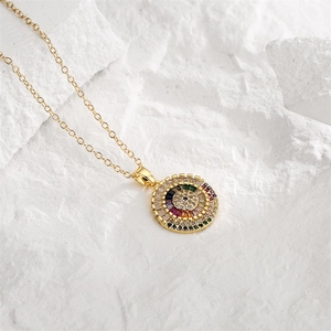 Detail of gold necklace with rainbow zircon micro-pave round palm pendant on stone