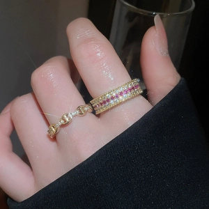Dettaglio di anelli sovrapponibili placcati oro 18k con zirconi e design a catena cava