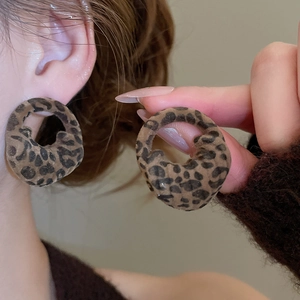 Close-up of leopard print flocked round earrings with warm texture on model's ear