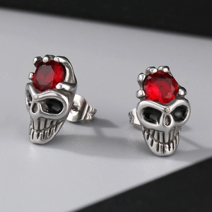 Macro detail of gothic skull stud earrings with red crystal inlay and vintage silver finish