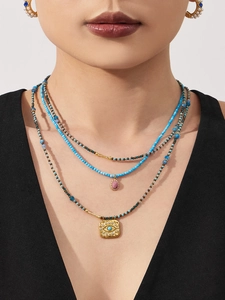 Close-up of turquoise layered necklace set with Evil Eye pendant and pearl earrings
