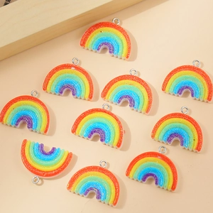 Flat lay of rainbow resin pendants with glitter finish and small metal rings for DIY
