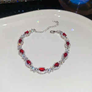 Close-up of silver bracelet featuring nine oval red zircons with halo diamond settings