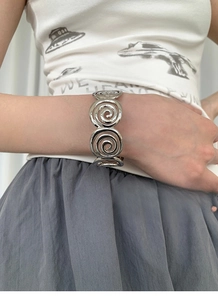 Close-up of a silver spiral hollow ring bracelet on a wrist with minimalist design