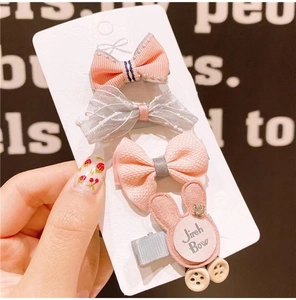 Close-up of 4 cute fabric bows and bunny hair clips set on a white card display