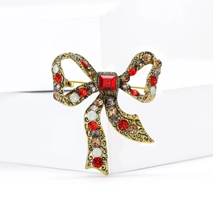 Detailed macro shot of vintage gold bow brooch with sparkling red and amber rhinestones