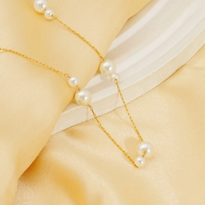 Collier élégant ajustable en acier doré avec perles blanches sur fond de satin jaune