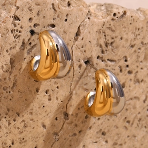 Detailed view of bicolor teardrop earrings in gold and silver on a textured stone surface