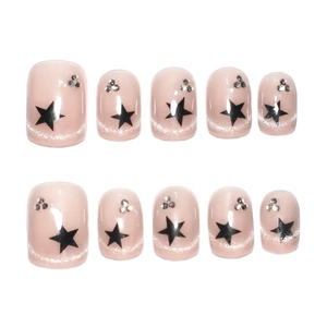 Short square press-on nails in nude pink with black stars and sparkling rhinestones