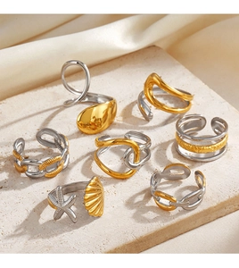 Detail of two-tone chain and shell design open rings on a textured stone surface