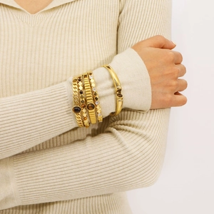 Stack of gold stainless steel bangles with tiger eye stones and zircon on a model's wrist