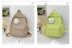 Detail view of khaki and green backpacks featuring plush pins and side fashion labels