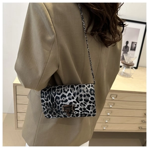 Detailed close-up of leopard print crossbody bag with metallic chain and twist lock