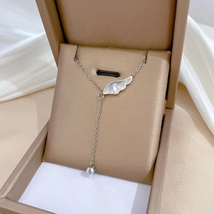Detail of angel wing necklace with white mother of pearl and zircon in gold jewelry box