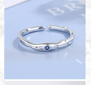 Détail d'une bague argentée torsadée ornée d'un zircon bleu rond serti au centre