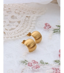 Detailed close-up of C-shaped matte 18K gold plated titanium steel hoop earrings on lace