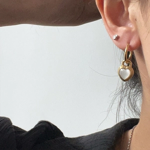 Detailed close-up of a heart-shaped lock earring with gold finish and mother-of-pearl inlay