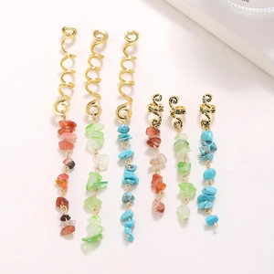 Macro view of gold spiral hair rings with natural gemstone pendants on white background