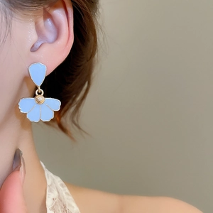 Detailed close-up of light blue enamel petal earrings with gold stamen on model