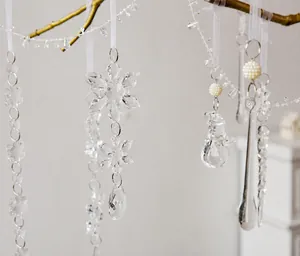 Macro shot of acrylic snowflake and droplet pendants hanging on golden branches
