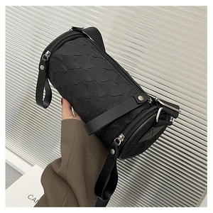 Detail of black cylindrical crossbody bag with embossed texture and adjustable strap