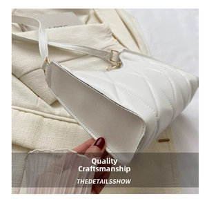 Close-up of a white quilted crossbody bag with detailed gold zipper and hardware accents